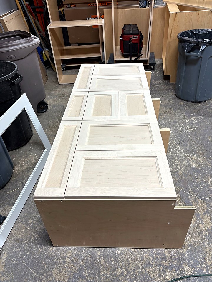 Paneled cabinet sides laid out on a base cabinet in the shop