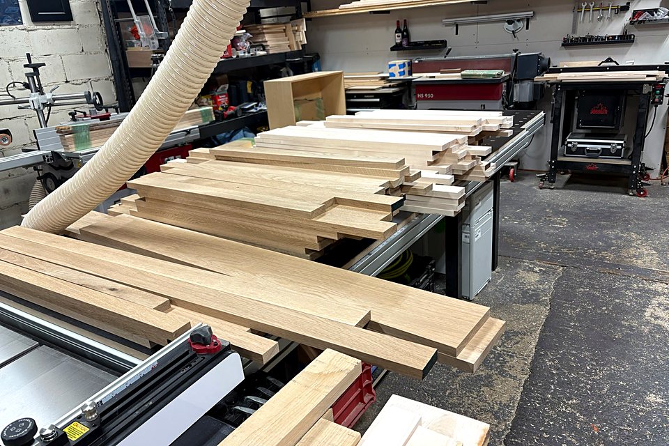Rough lumber stacked by the table saw, ready to be milled