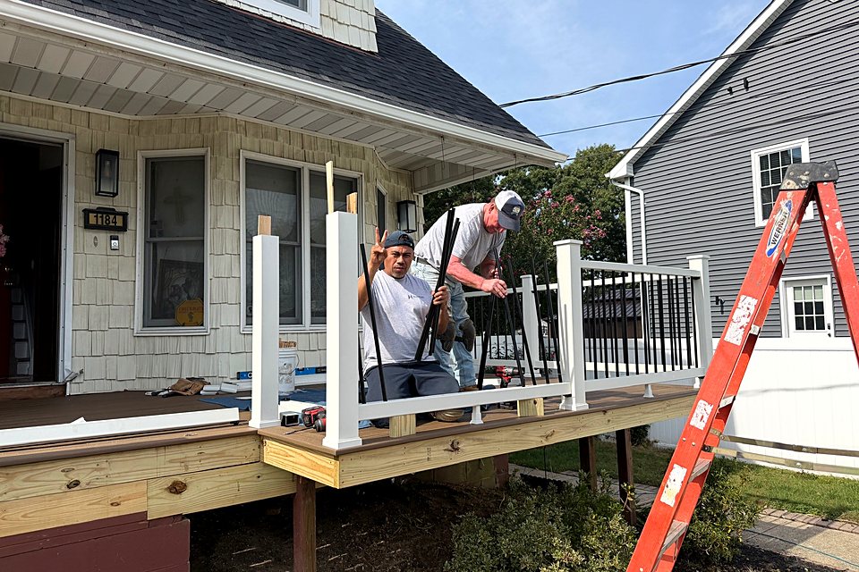 Two crew members installing the new porch railing