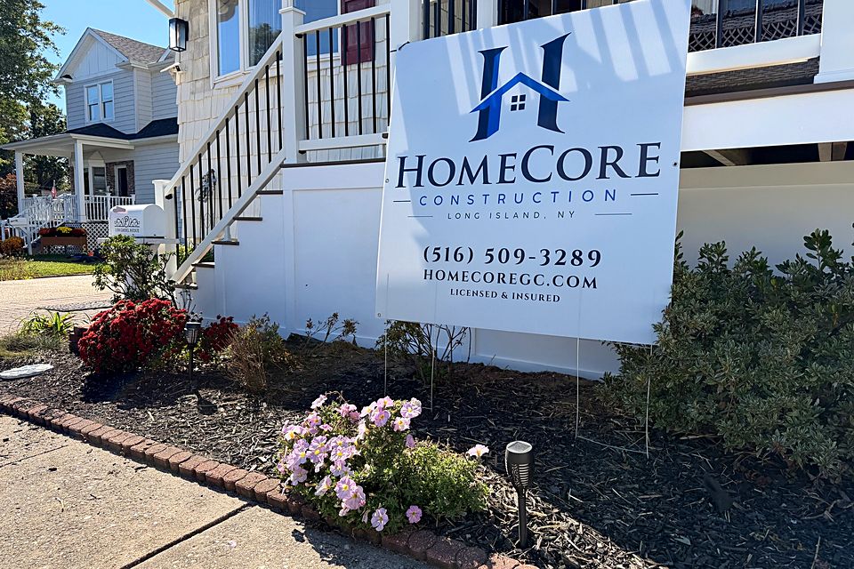 Finished porch and stairs behind a HomeCore Construction yard sign