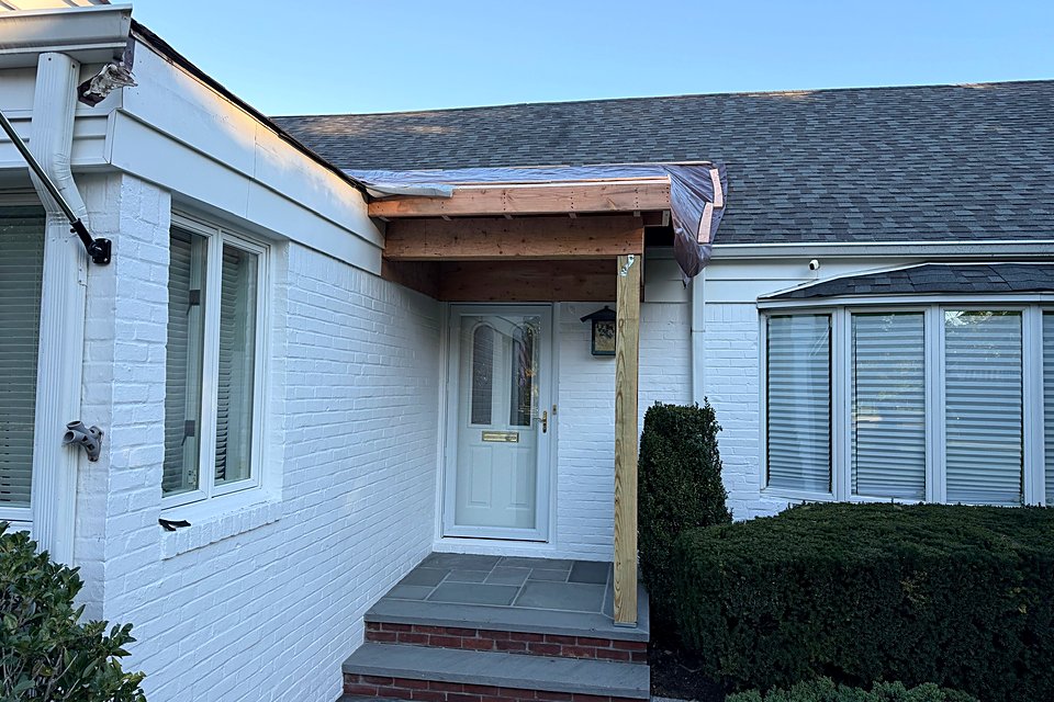 Framing: New portico roof framed over the front door on a wood post and beam.