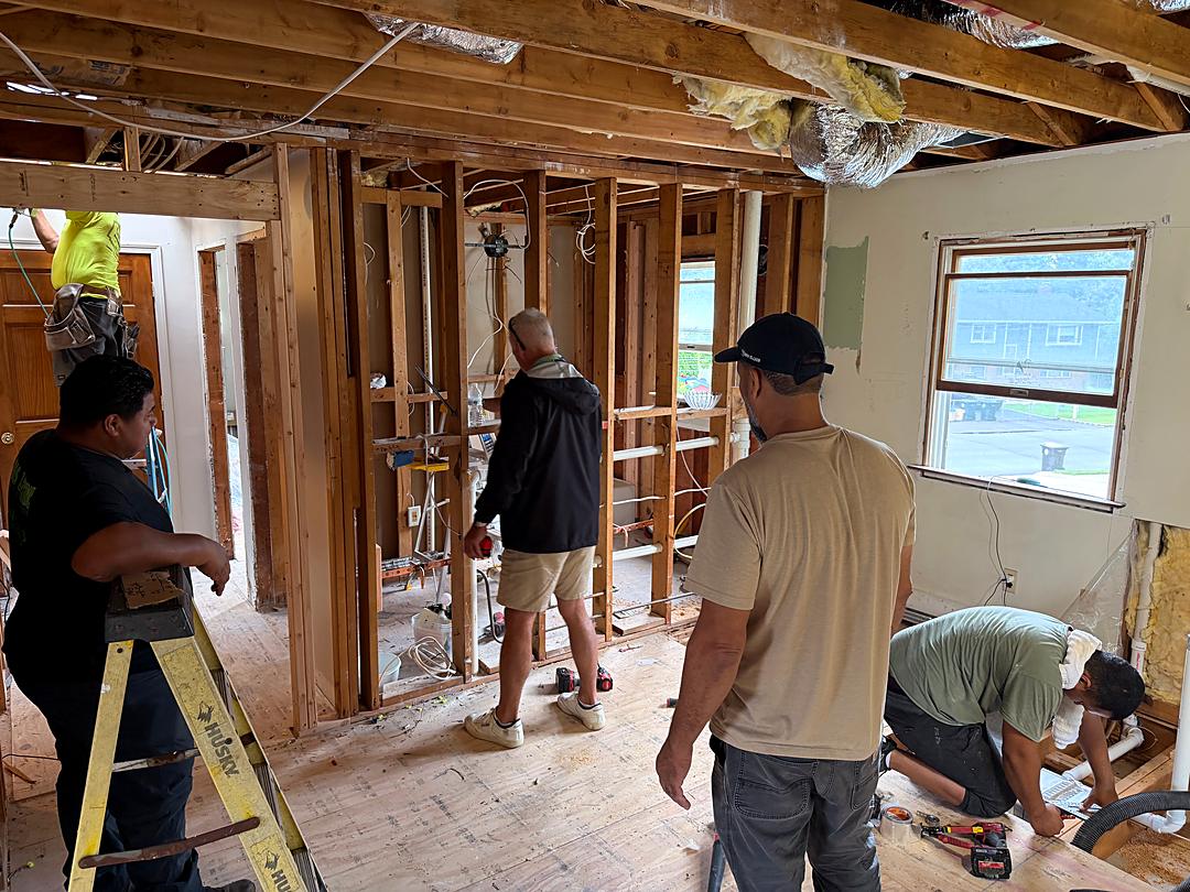 Crew working together on a gutted second floor as new framing and plumbing go in