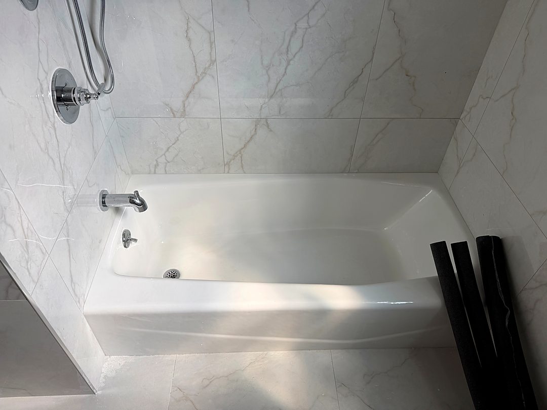 New bathtub with a marble-look tile surround and chrome fixtures