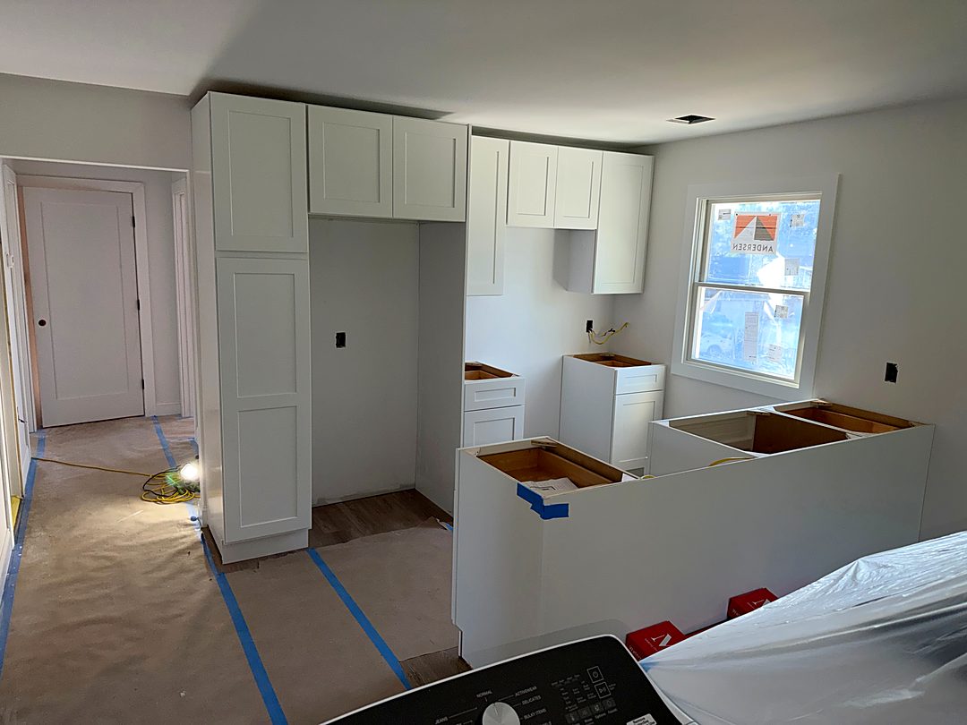 New white shaker kitchen cabinets being installed in the renovated kitchen