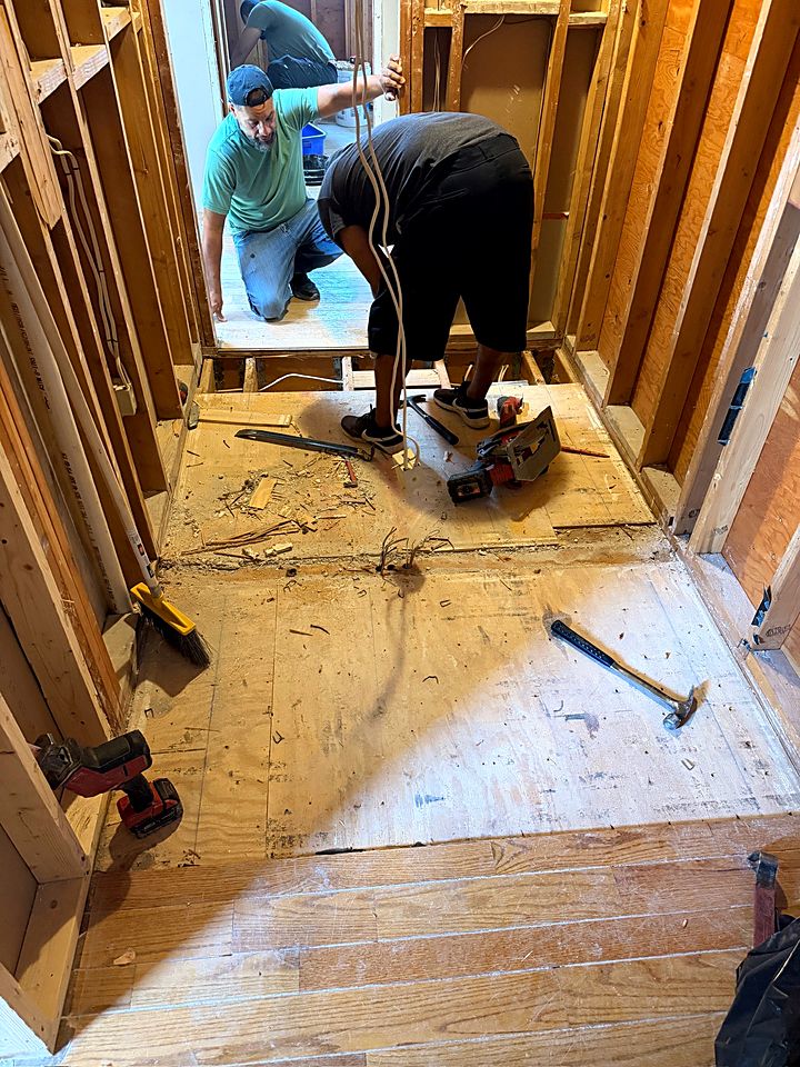 Crew cutting in new subfloor in a gutted room