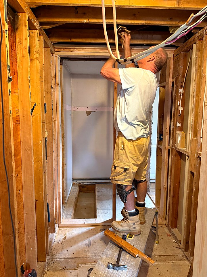 Crew member running new wiring through a framed doorway