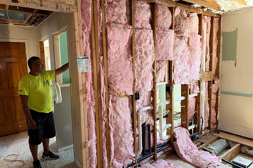 Crew member in a room with the new insulation going into the walls