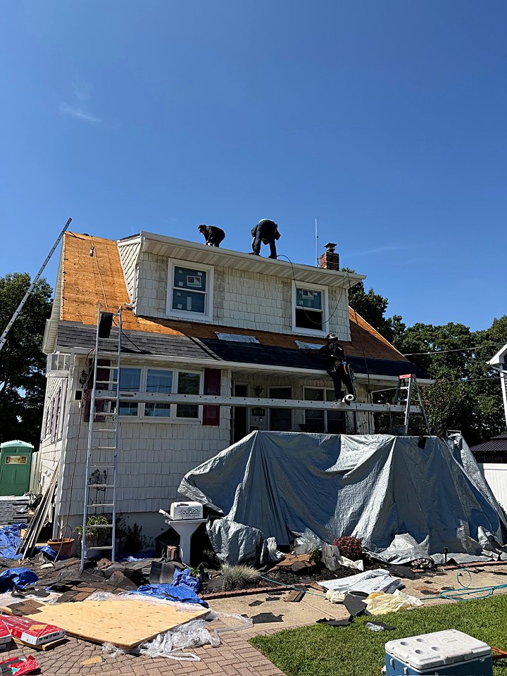 The house with the roof crew at work up top and the yard staged for the job