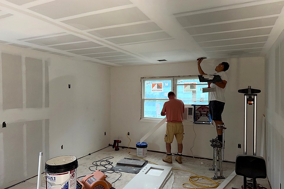 Crew working on a ladder and stilts under a new coffered ceiling