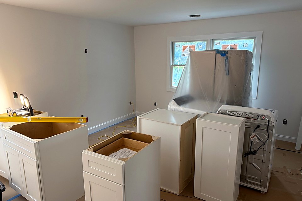 New white base cabinets staged in the kitchen ahead of install
