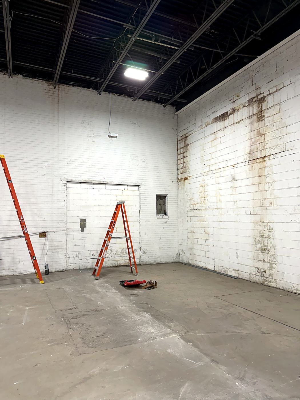Bare block room with stained walls and an open ceiling before the commercial build-out