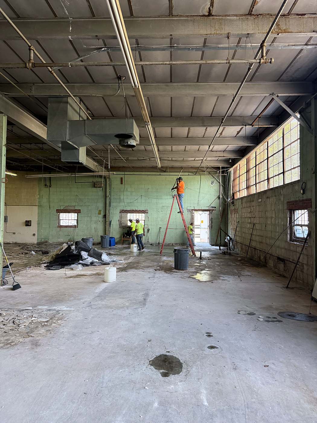 Crew member on a ladder working overhead in the cleared commercial space