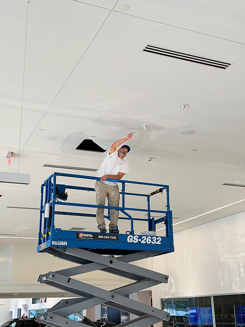 Crew member on a scissor lift working on a showroom ceiling