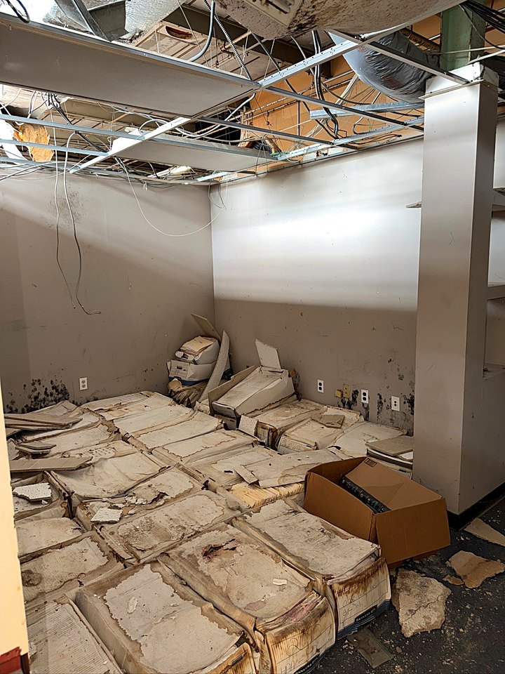 Old ceiling tiles and grid piled on the floor during demolition